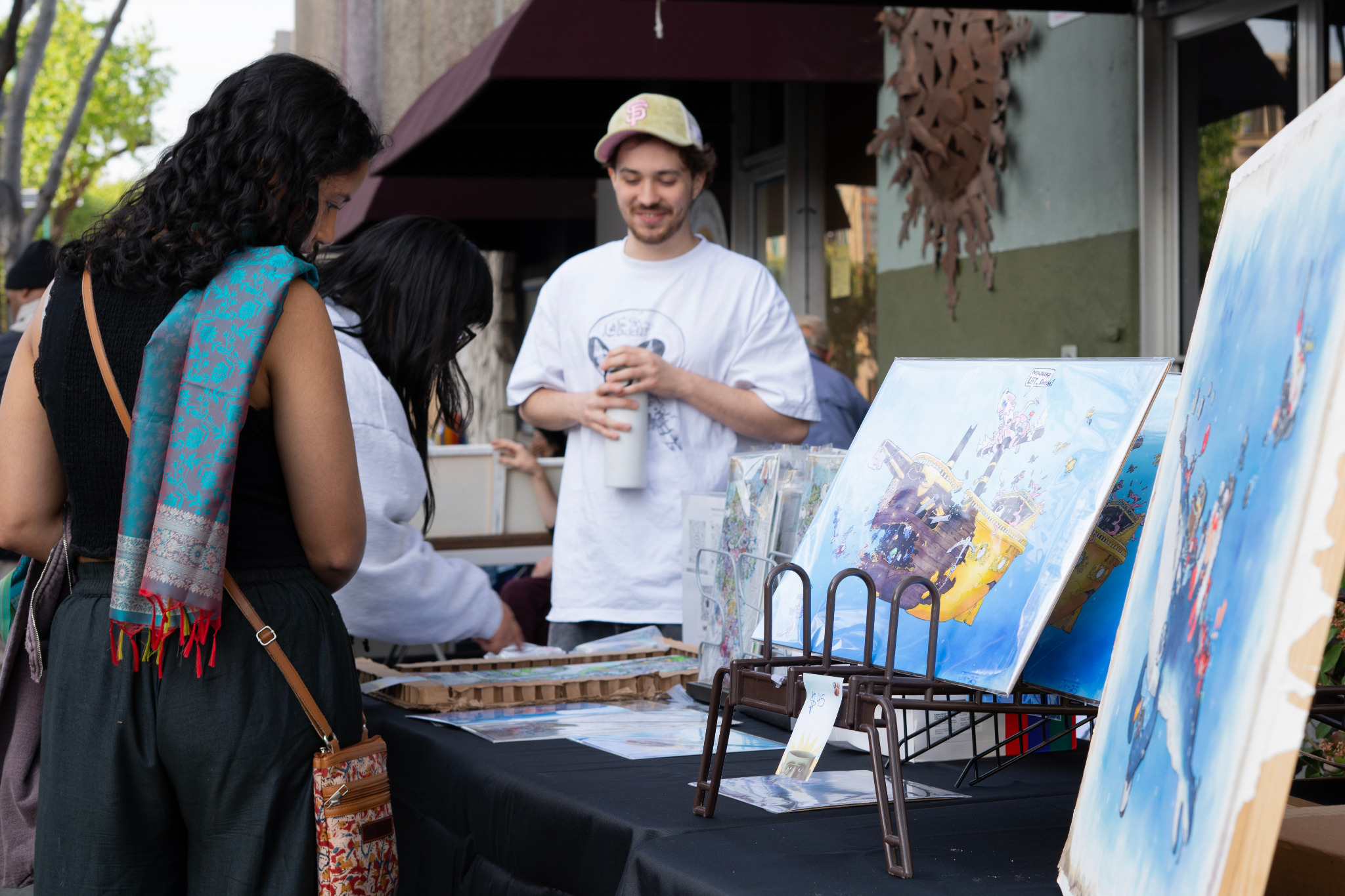 People browsing artwork at a Vallejo Art Walk table.