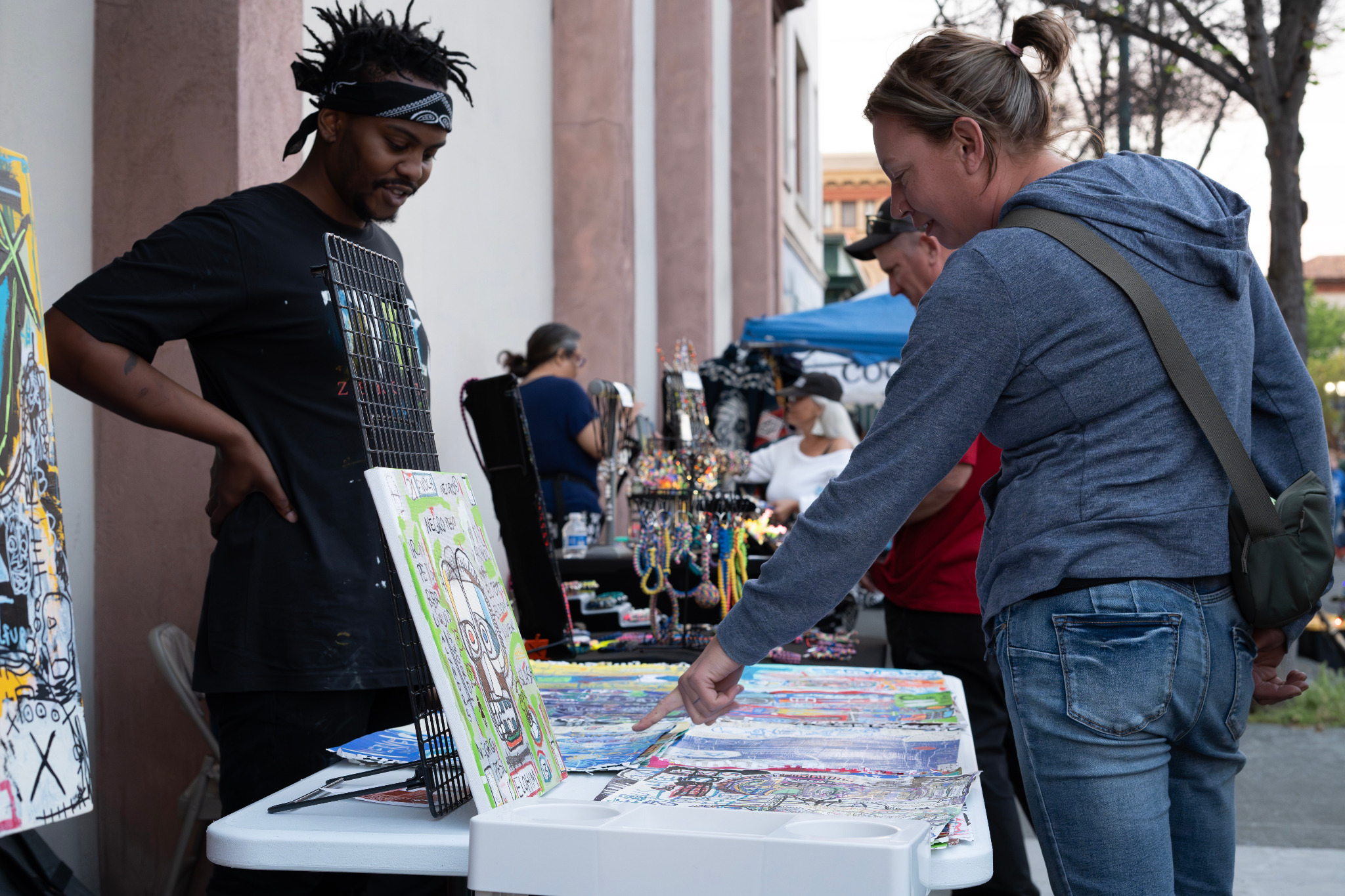 A person browsing artwork at an outdoor table.
